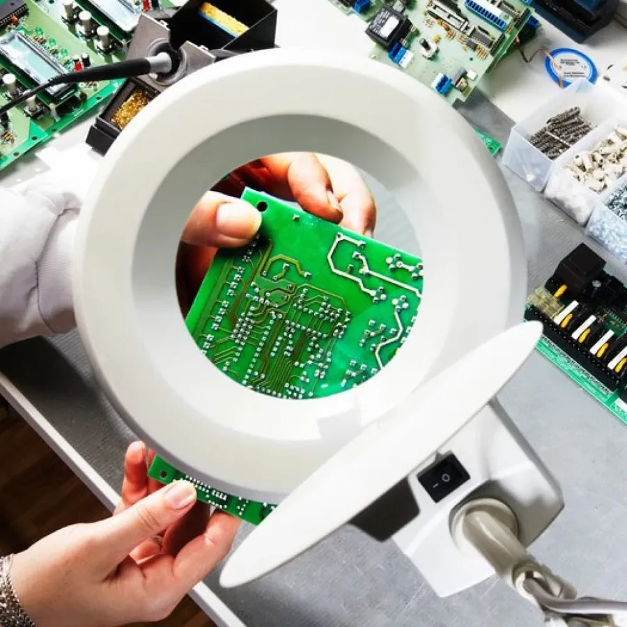 A person inspecting a PCB using a microscope.