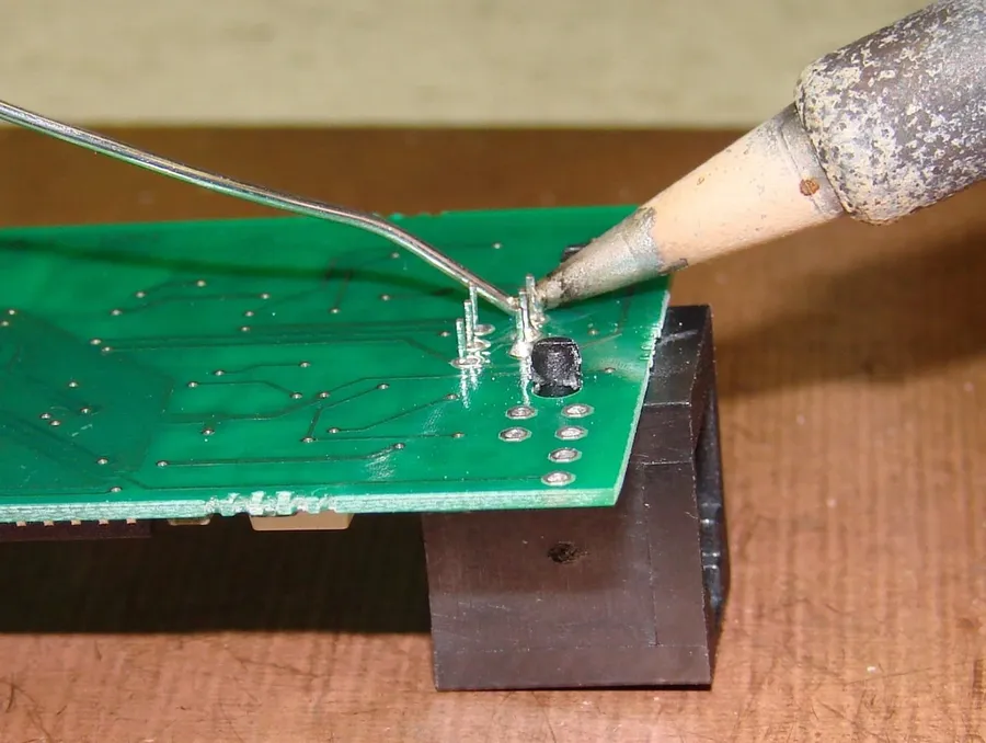 A hand soldering components onto a circuit board.