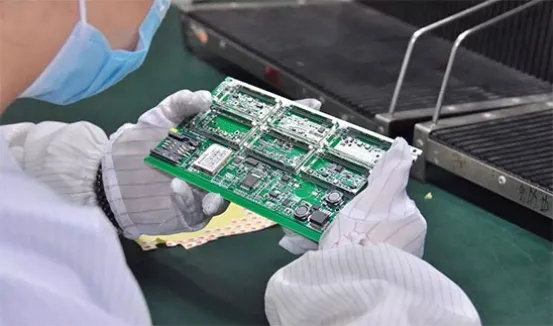 A close-up of a person inspecting a PCB with a magnifying glass.