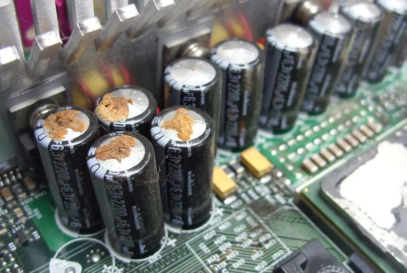 Close-up image of a burnt capacitor on a circuit board.
