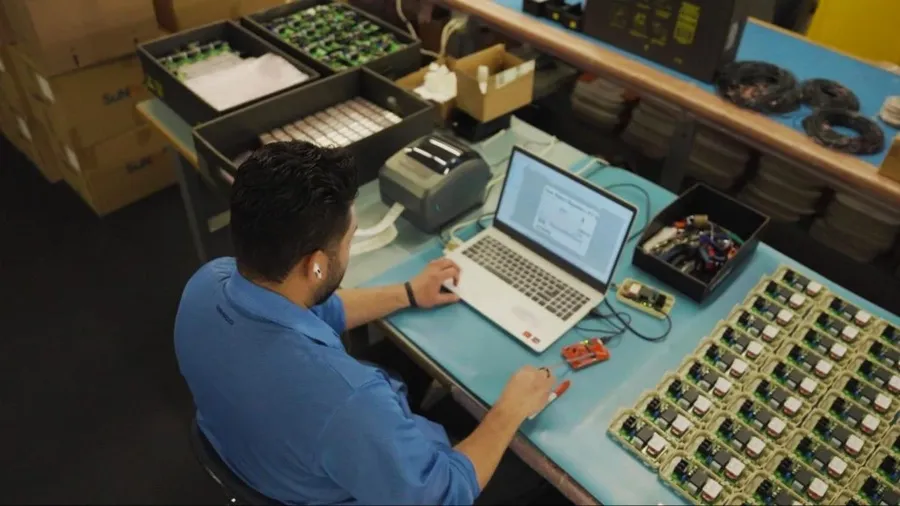 A PCB design engineer working on a computer with PCB layout software visible on the screen.