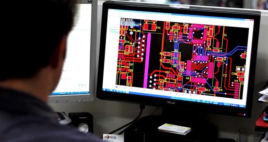 A modern PCB design workstation setup with multiple monitors and equipment.