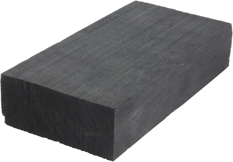 A charcoal soldering block with metal being soldered on top.