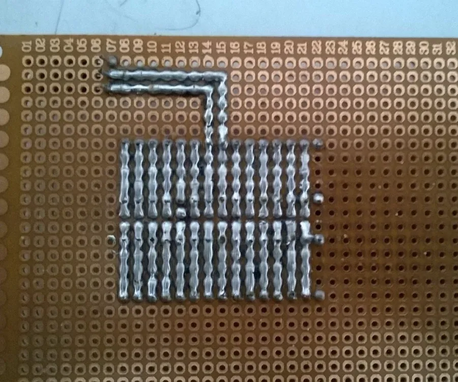 A person soldering components onto a universal PCB board.