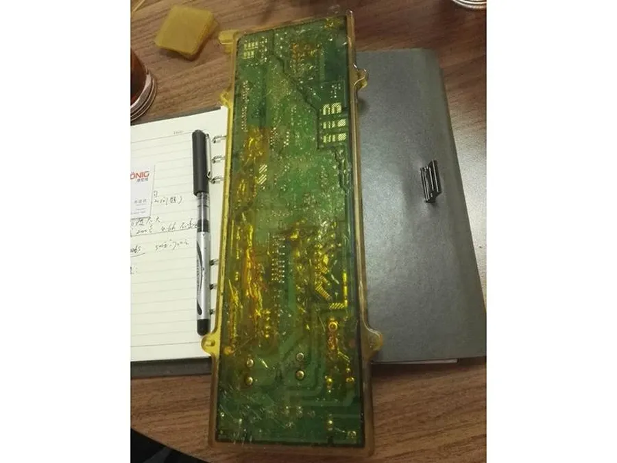 A hot melt glue gun applying glue onto a PCB.