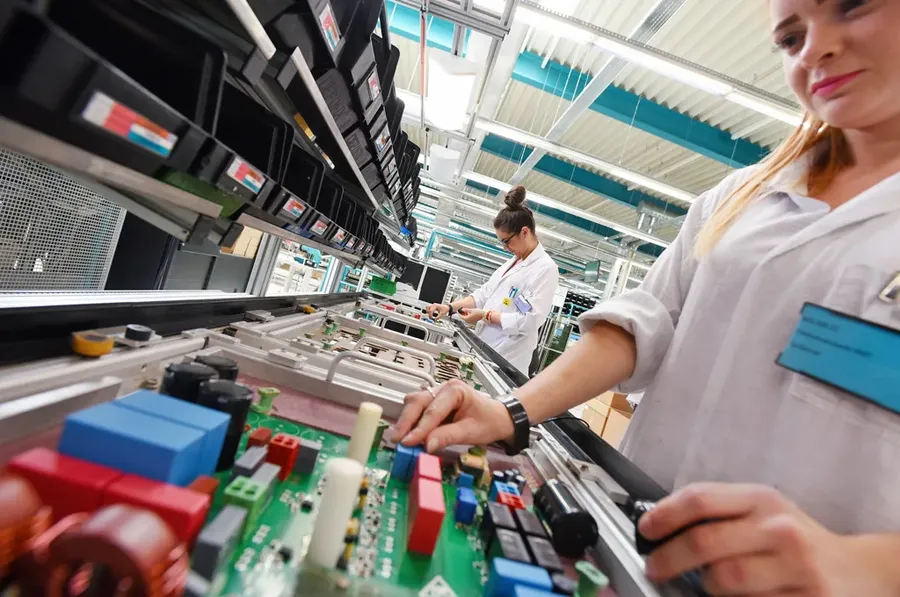 A view inside a PCB manufacturing facility with various equipment and workers.