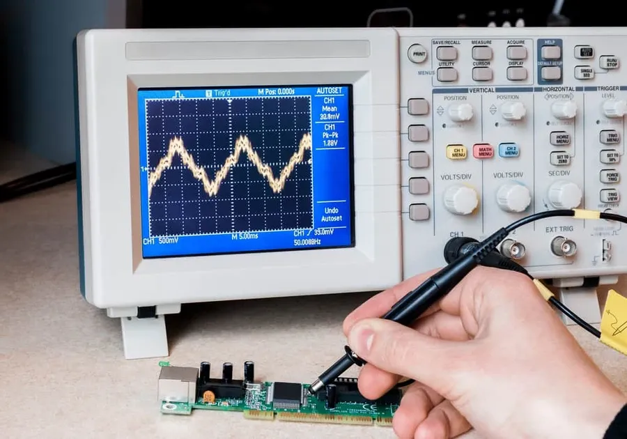 A person using a microscope to inspect electronic components for quality and authenticity.
