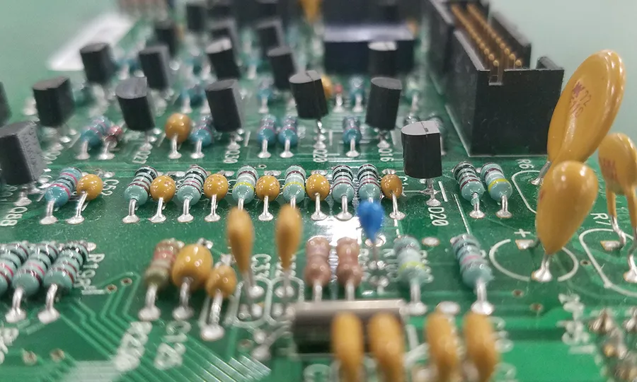 A person inserting through-hole components into a PCB.