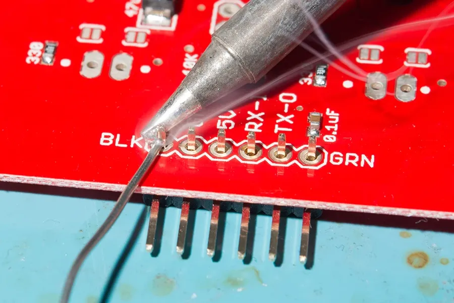 A technician inspecting solder joints on a through-hole PCB.