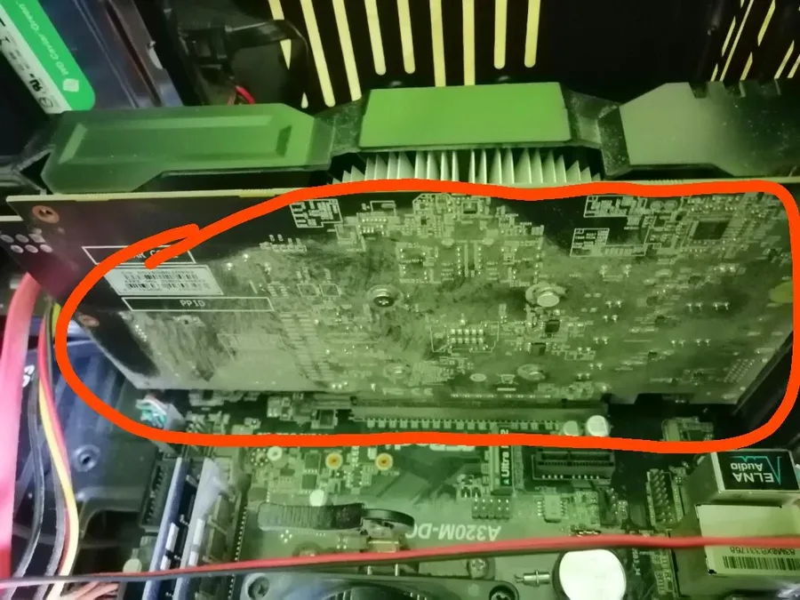 Hands cleaning a graphics card PCB with a brush.