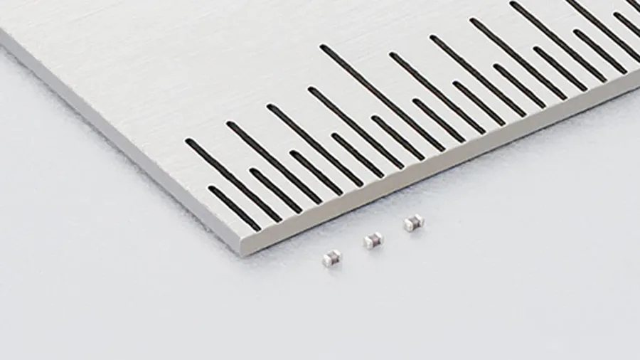 Extremely small 006003-inch MLCC capacitor, with a size comparison object.