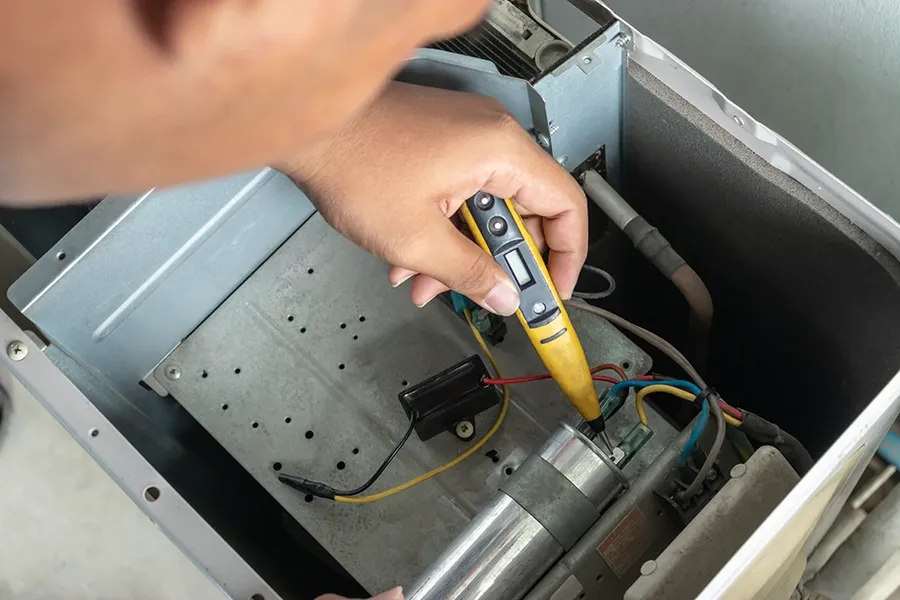 An AC capacitor being inspected as part of maintenance.